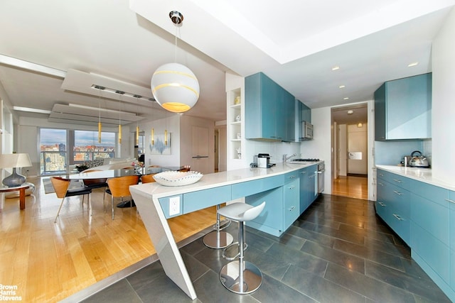 303 E 57th St Unit 46E, New York City, NY 10022 - kitchen with blue cabinets, open shelves, stainless steel microwave, a peninsula, and light countertops