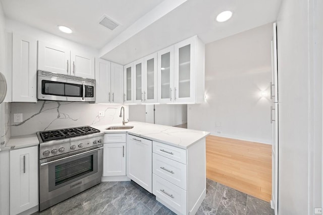 kitchen featuring sink, stainless steel appliances, kitchen peninsula, and white cabinets