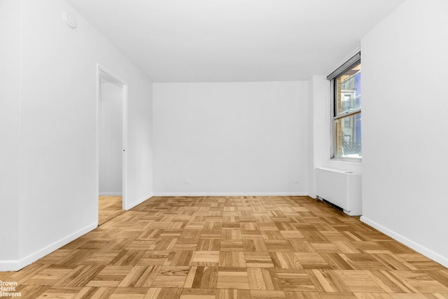 spare room featuring radiator and baseboards