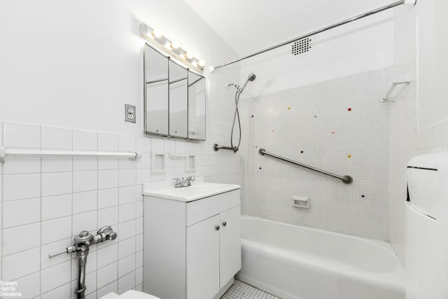 full bathroom featuring toilet, tile walls, washtub / shower combination, tile patterned flooring, and vanity