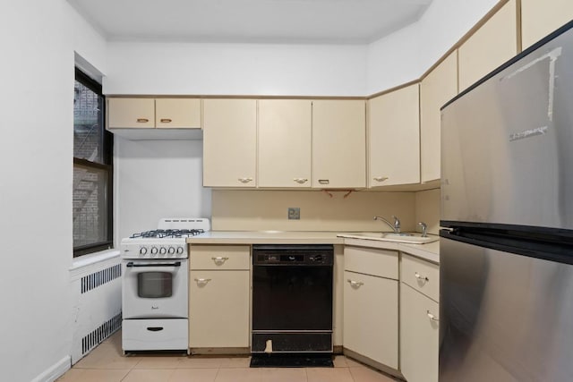 kitchen featuring black dishwasher, light countertops, cream cabinets, freestanding refrigerator, and white range with gas stovetop