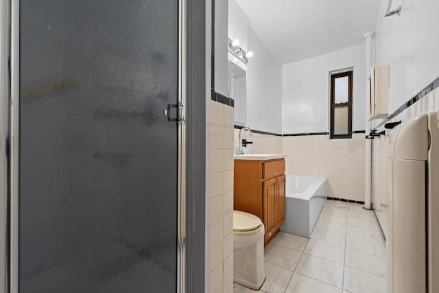 bathroom with tile walls, toilet, a stall shower, vanity, and a bath