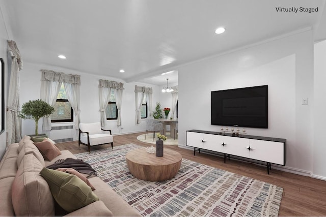 living area with an inviting chandelier, baseboards, radiator heating unit, and wood finished floors