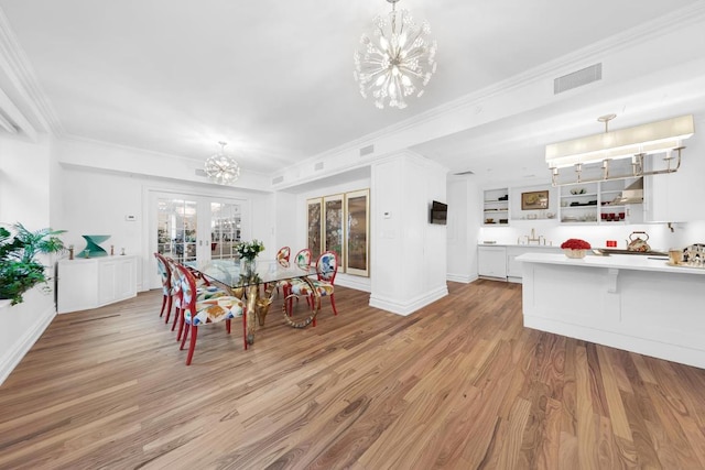 dining room with crown molding, an inviting chandelier, and light wood-type flooring