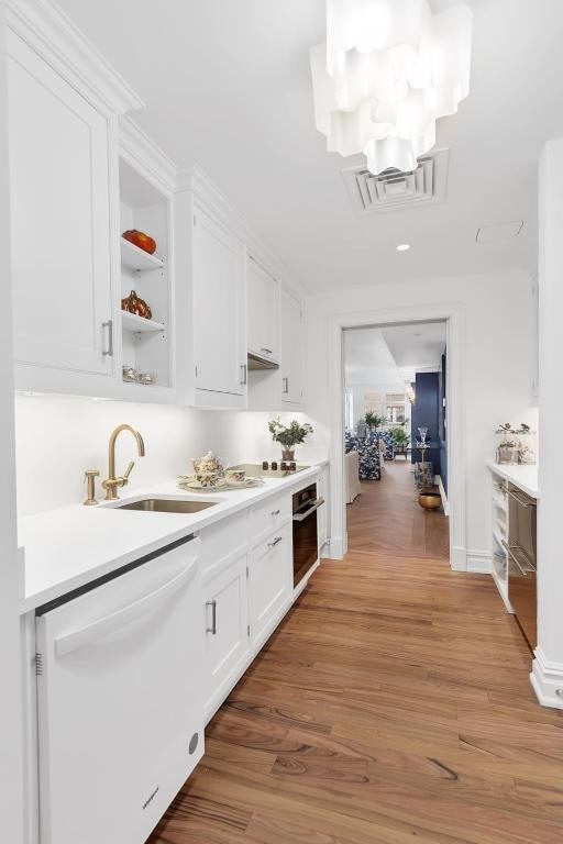 bar with hardwood / wood-style floors, black oven, white cabinetry, sink, and white dishwasher