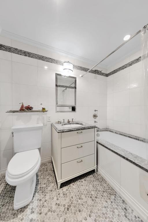 full bathroom with shower / bathing tub combination, tile walls, toilet, and vanity