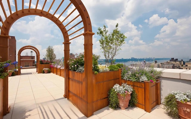 view of patio featuring exterior fireplace, fence, a city view, and a pergola