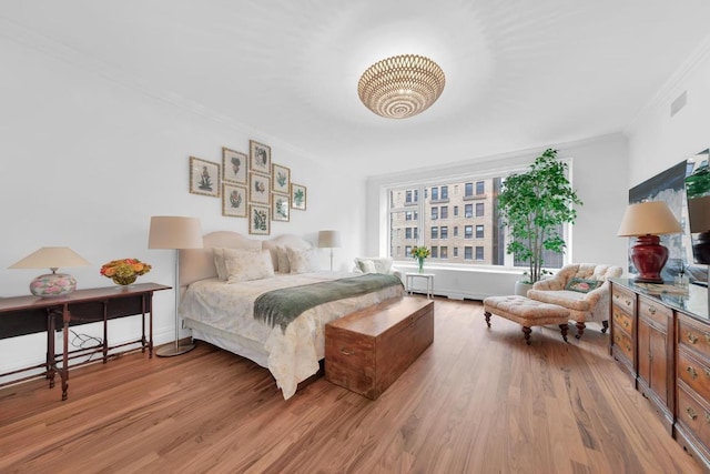 bedroom with crown molding and light hardwood / wood-style floors