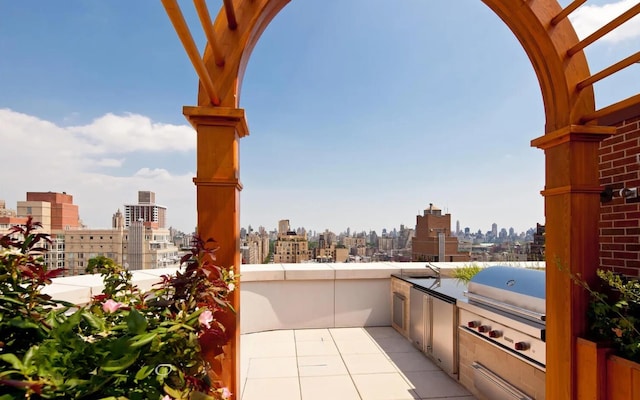 view of patio / terrace featuring a balcony, exterior kitchen, a grill, and a city view