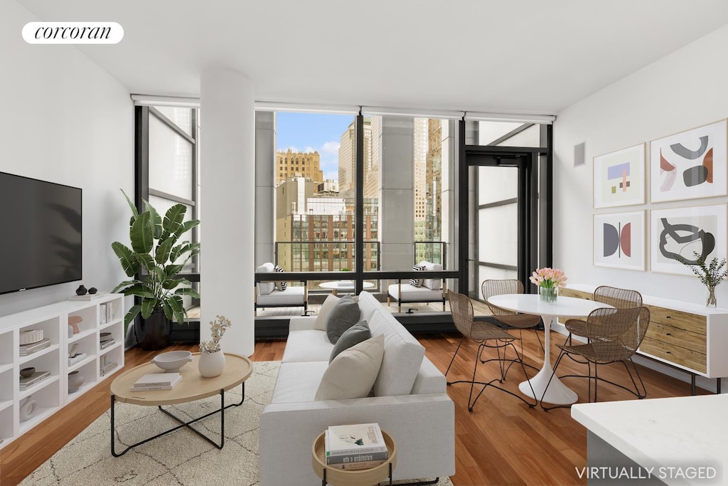 living area with expansive windows, a view of city, wood finished floors, and visible vents