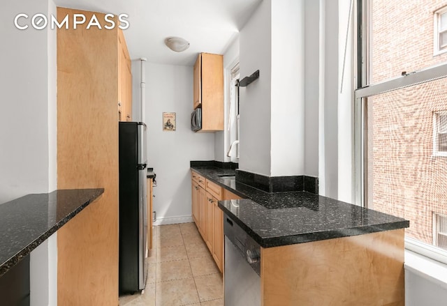 kitchen featuring dark stone counters, stainless steel appliances, sink, and light tile patterned floors