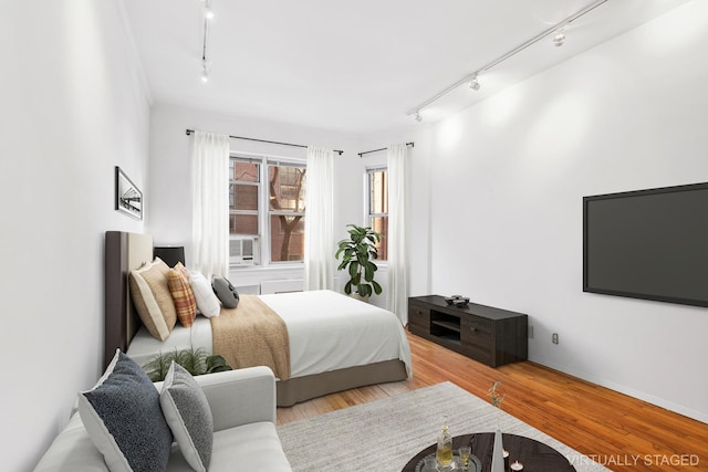 bedroom with rail lighting and wood finished floors