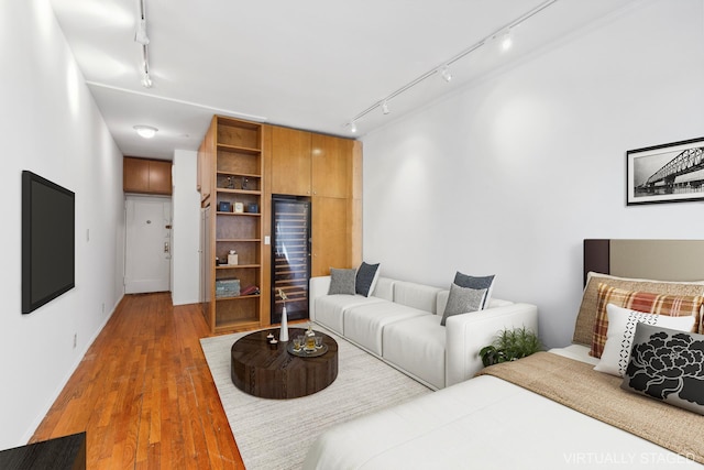 living room featuring wine cooler, track lighting, and light wood-style floors