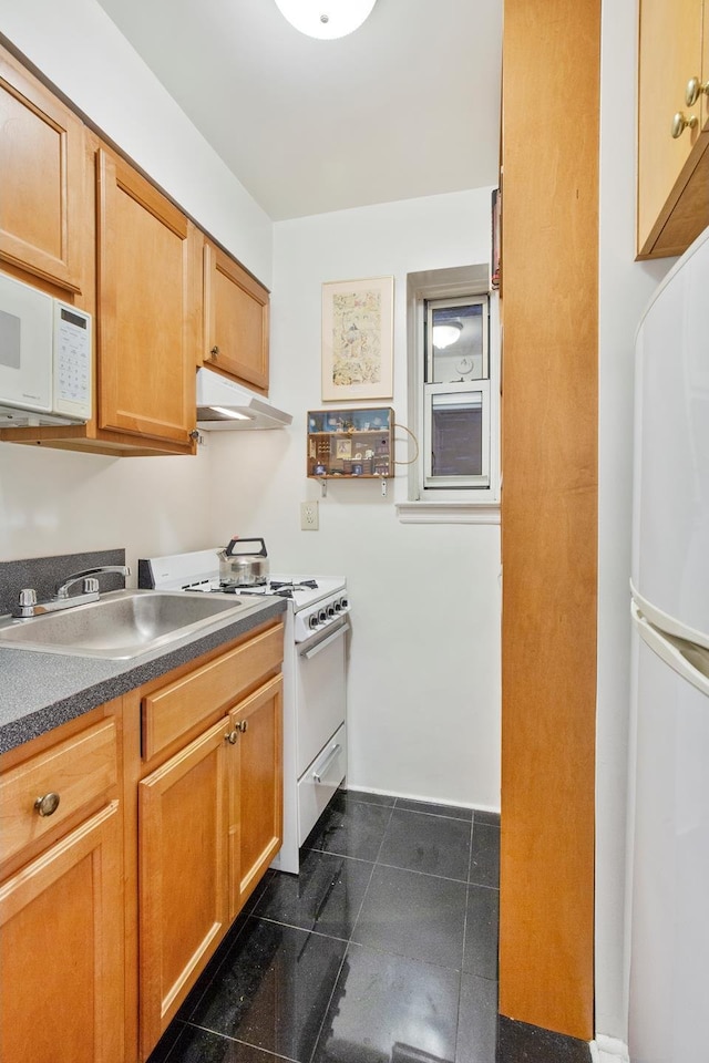 kitchen with under cabinet range hood, white appliances, dark countertops, and dark tile patterned flooring