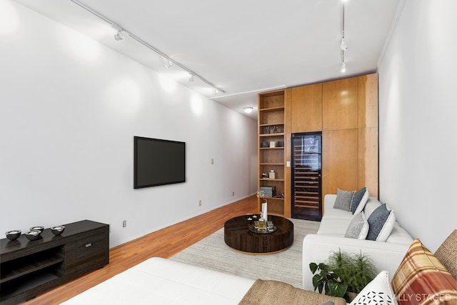 living area with beverage cooler, track lighting, and light wood-style flooring