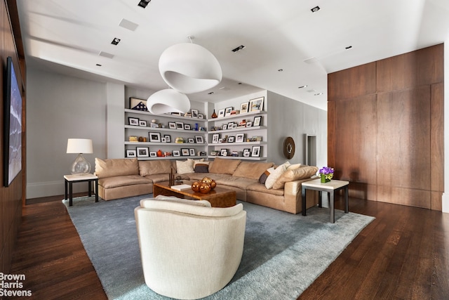 living area featuring dark wood-style floors, built in shelves, and visible vents