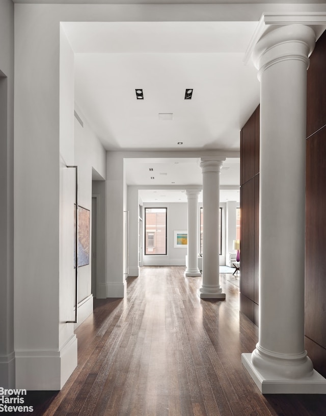 hallway featuring ornate columns, baseboards, and dark wood-style floors