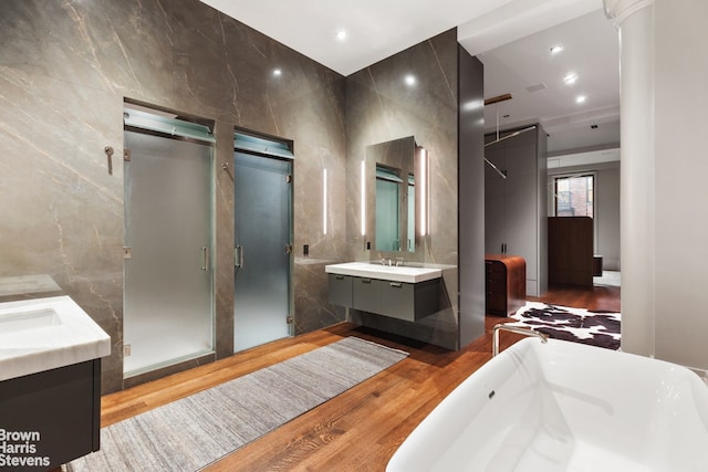 bathroom featuring tile walls, a freestanding bath, a shower stall, vanity, and wood finished floors