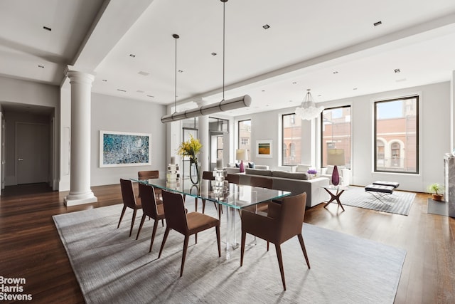 dining room with decorative columns, hardwood / wood-style floors, and an inviting chandelier