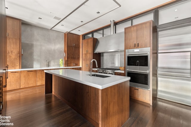 kitchen featuring tasteful backsplash, extractor fan, sink, an island with sink, and stainless steel appliances