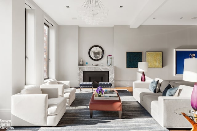 living area with a fireplace, wood finished floors, beam ceiling, and a notable chandelier