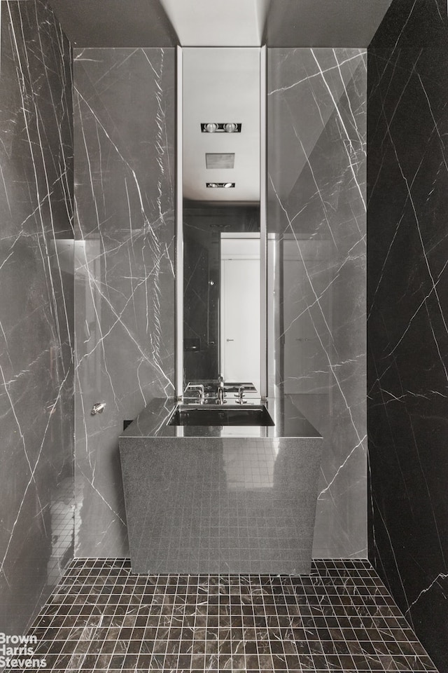 bathroom with a sink and tile walls