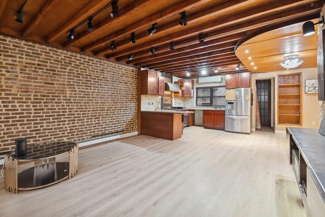 kitchen featuring brick wall, appliances with stainless steel finishes, track lighting, a wall unit AC, and light wood-type flooring