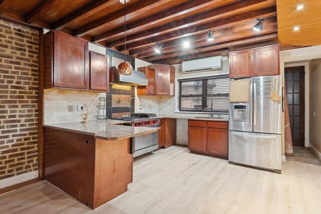 kitchen featuring brick wall, appliances with stainless steel finishes, track lighting, a wall unit AC, and light wood-type flooring