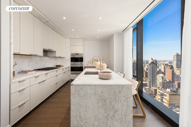 kitchen with stainless steel double oven, a sink, white cabinets, light countertops, and a view of city