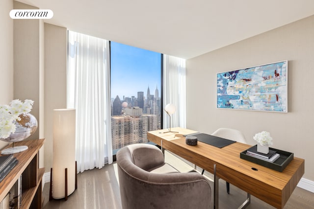 home office with a view of city, visible vents, expansive windows, wood finished floors, and baseboards