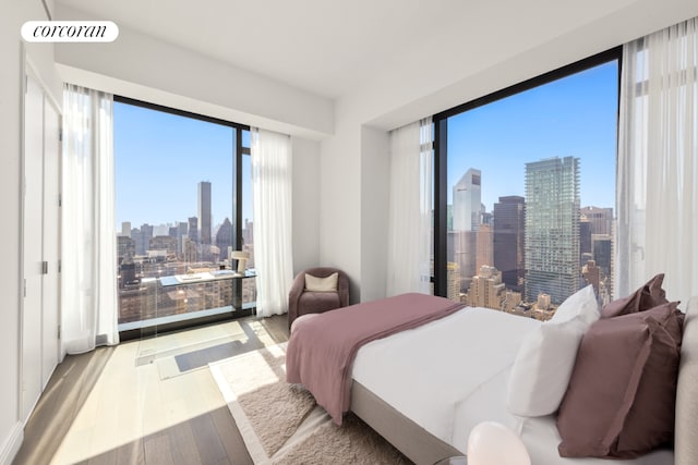 bedroom with light wood-style floors, visible vents, and a city view