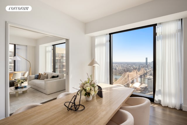 dining room featuring a water view, wood finished floors, visible vents, and a city view