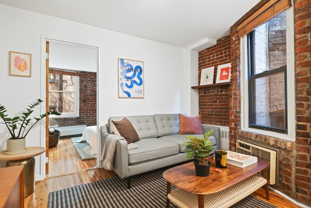 living room with brick wall, wood finished floors, and radiator