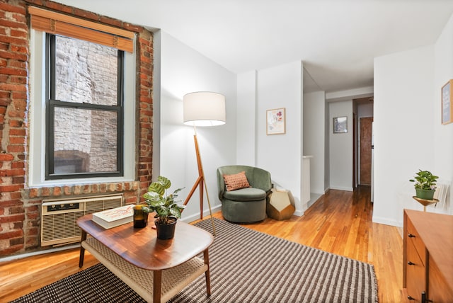 sitting room with baseboards, a wall mounted AC, vaulted ceiling, and light wood-style floors