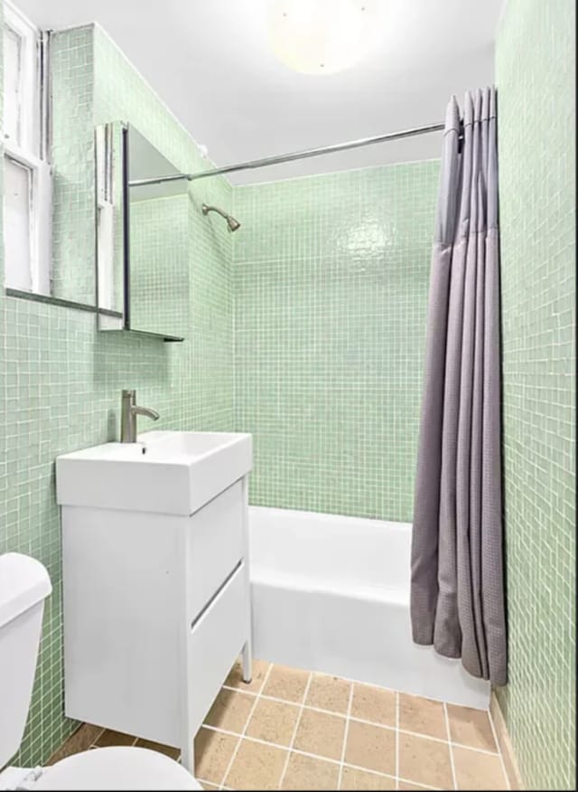 full bath with vanity, shower / bathtub combination with curtain, toilet, and tile walls