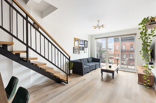 living room with a city view, a chandelier, stairs, and light wood finished floors