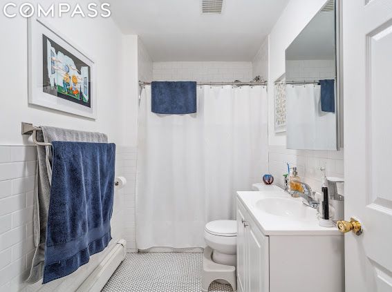 bathroom with toilet, tile walls, vanity, and curtained shower