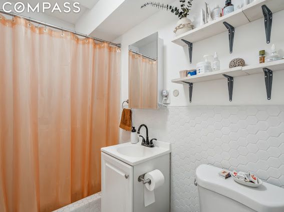 bathroom featuring toilet, vanity, and walk in shower