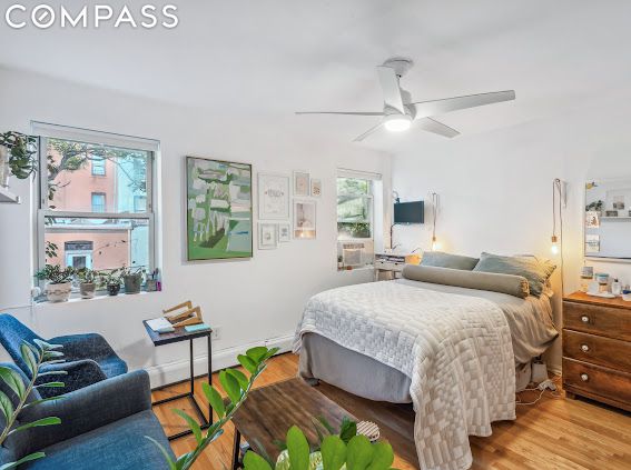 bedroom featuring ceiling fan, multiple windows, and light hardwood / wood-style flooring