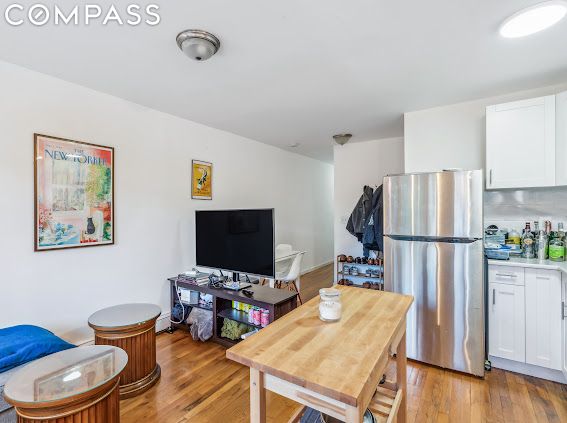 kitchen with backsplash, white cabinets, light hardwood / wood-style flooring, and stainless steel refrigerator