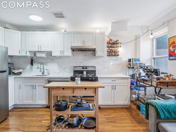 kitchen featuring backsplash, appliances with stainless steel finishes, and white cabinetry