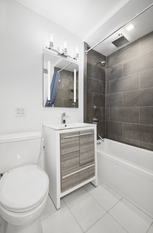 full bathroom with tiled shower / bath combo, vanity, tile patterned floors, and toilet