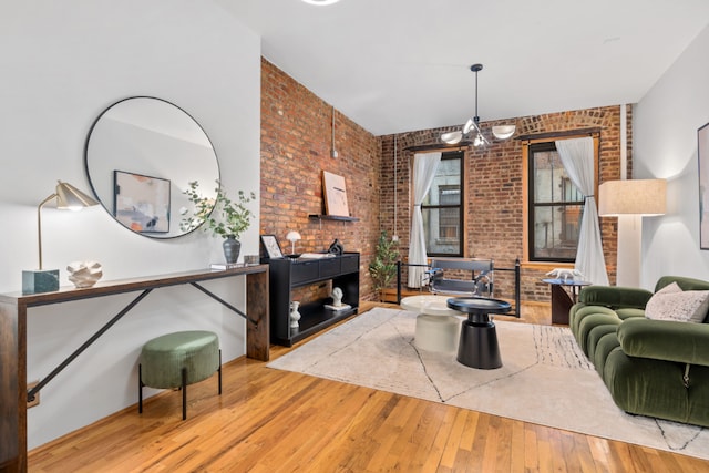 living room with light wood-type flooring, brick wall, and a chandelier