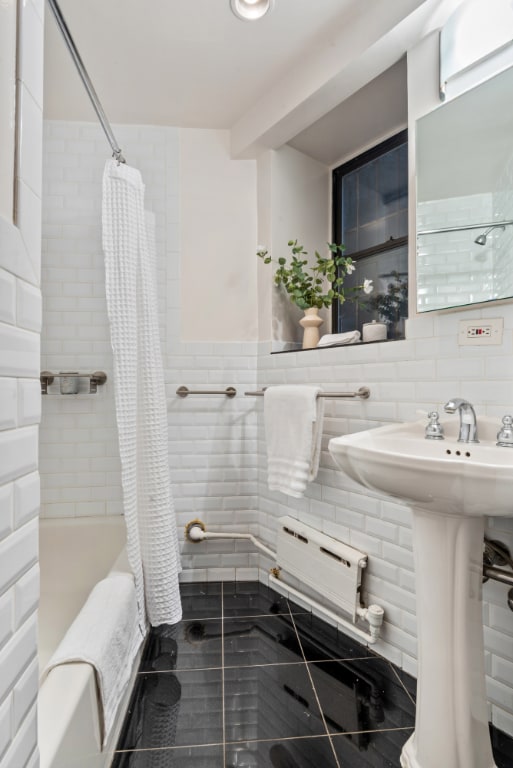 bathroom with decorative backsplash, tile walls, shower / bath combo, and sink