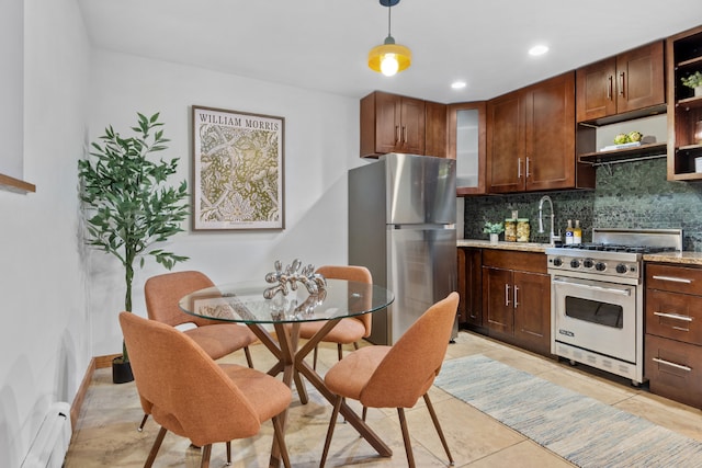 kitchen featuring appliances with stainless steel finishes, decorative light fixtures, a baseboard heating unit, light stone counters, and light tile patterned floors