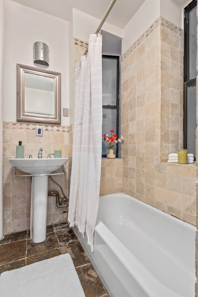 full bathroom with a sink, shower / bath combo with shower curtain, and tile walls