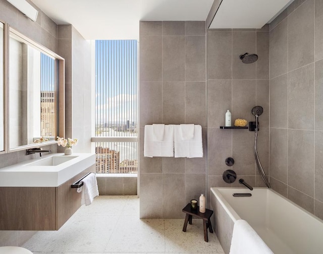 bathroom with tile patterned floors, vanity, tiled shower / bath combo, and tile walls