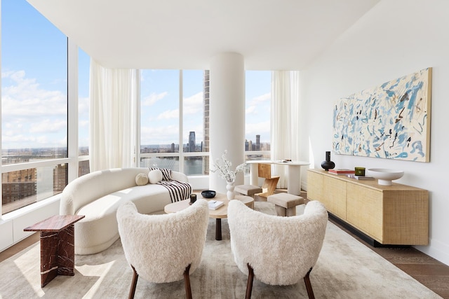 sitting room with floor to ceiling windows, a city view, and wood finished floors