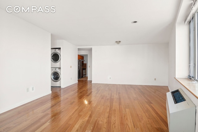 unfurnished living room featuring stacked washer / dryer and light wood-style flooring