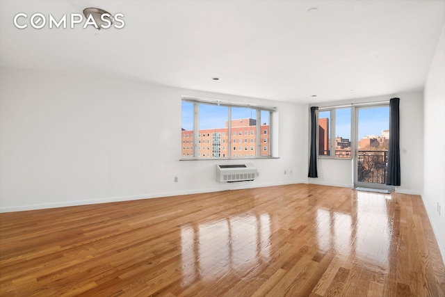 unfurnished room featuring baseboards, heating unit, a city view, and wood finished floors